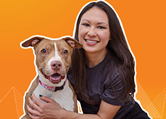 A Best Friends volunteer hugging a brown and white dog
