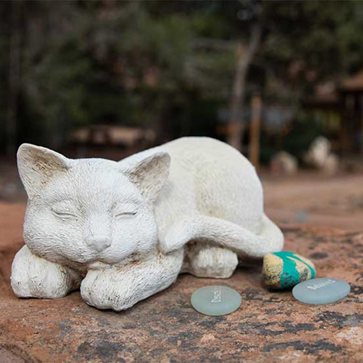 Sleeping cat statue with three green rocks in front